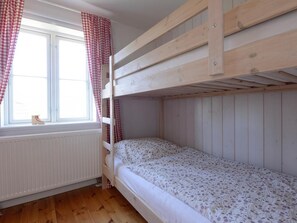 Ein Schlafraum mit Etagenbetten, einem Fenster und Vorhängen.