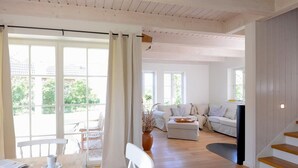 Un vaste espace de vie doté d’un plancher en bois, d’une table à manger avec des chaises, d’un canapé et d’un escalier.