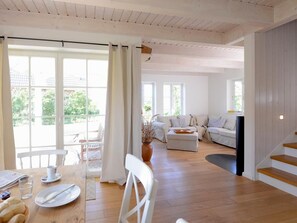 Ein geräumiger Wohnbereich mit Holzboden, einem Esstisch mit Stühlen, einer Couch und einer Treppe.