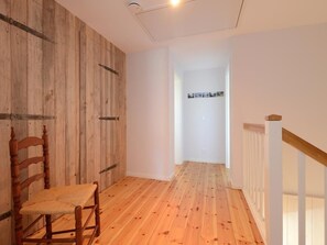 A hallway with wooden flooring and a wooden chair.