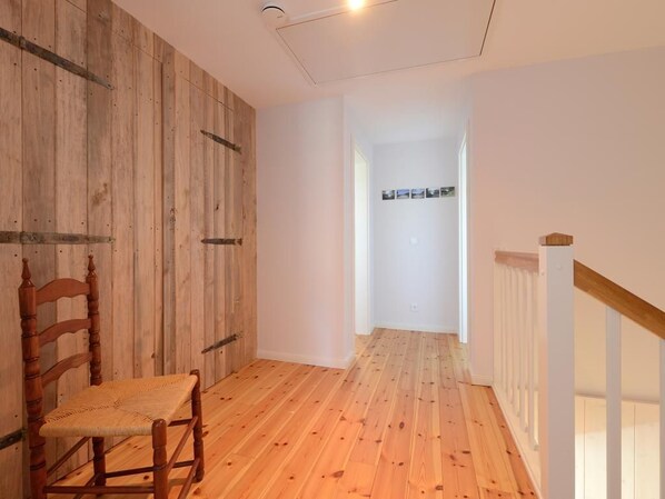 Un pasillo con suelo de madera y una silla de madera.