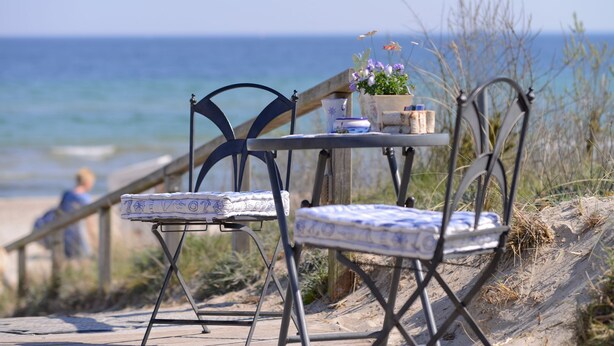 A beachside table with a chair, a small table, and a potted plant. - Urlauberdorf 40b, Deutschland (Ostseebad Boltenhagen)