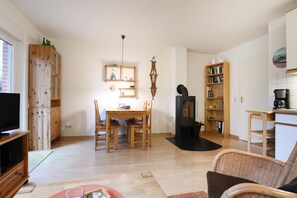 Ein gemütliches Wohnzimmer mit Fernseher, eine Essecke mit Tisch und Stühlen, ein Kamin und ein Bücherregal.
