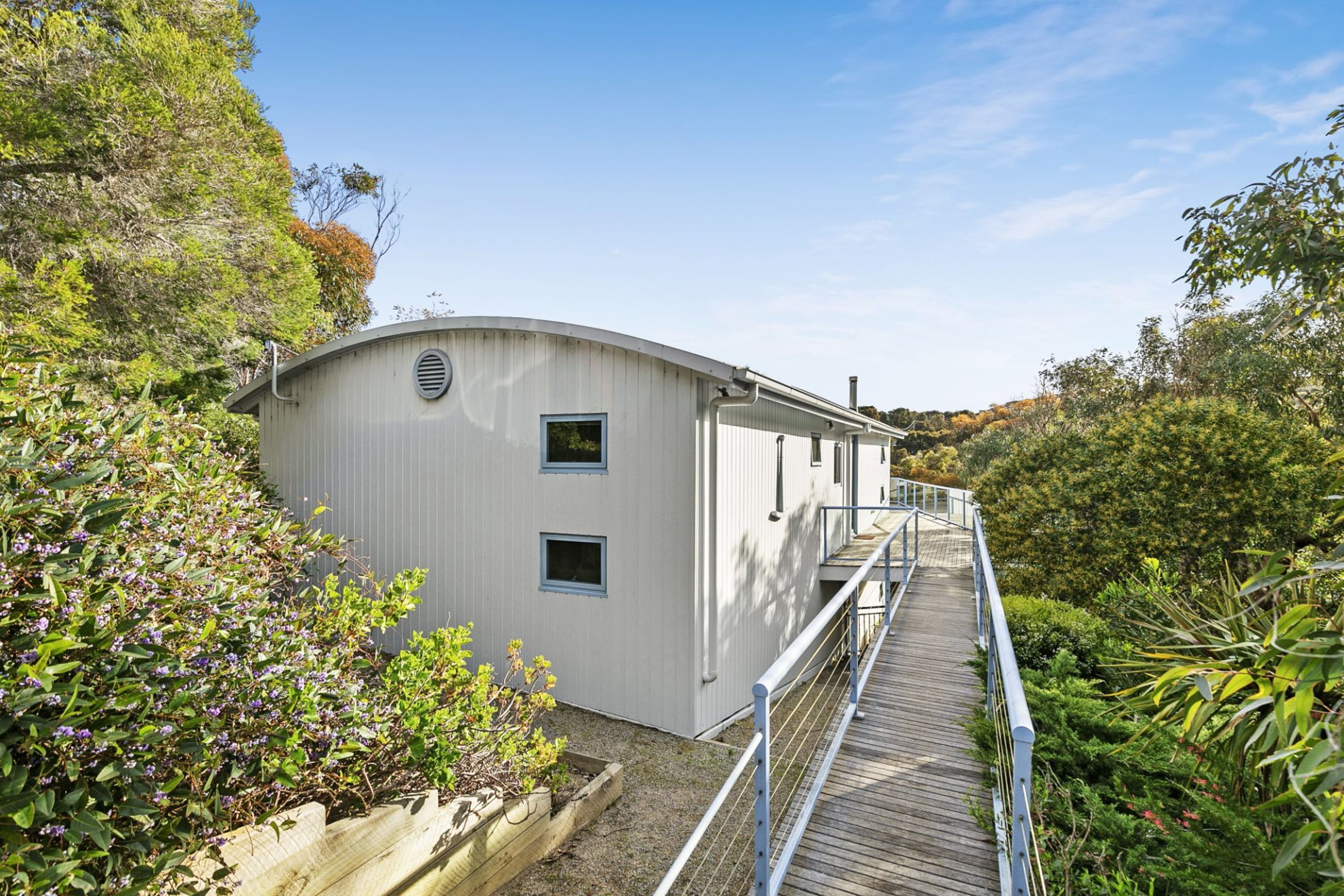 A building with a curved roof, a wooden deck, and a metal railing.