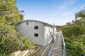 A building with a curved roof, a wooden deck, and a metal railing. - Caprica (Fairhaven)