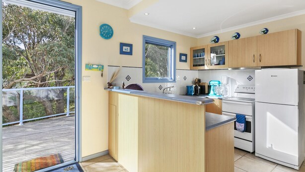 A modern kitchen with a central island, wooden cabinets, and a view of the outdoors. - Caprica (Fairhaven)