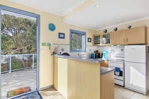 A modern kitchen with a central island, wooden cabinets, and a view of the outdoors.