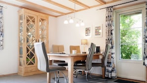 Een eetruimte met een houten tafel en stoelen, een kast met glazen deuren en een raam met gordijnen.