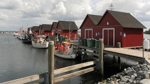 Een haven met rode gebouwen, liggende boten en een houten steiger.