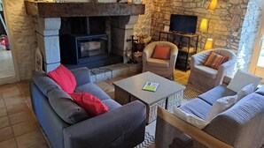 A cozy living room with a stone fireplace, comfortable seating, and a flat-screen TV.