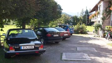 Een rij geparkeerde auto's in een oprit, met een gebouw aan de rechterkant.