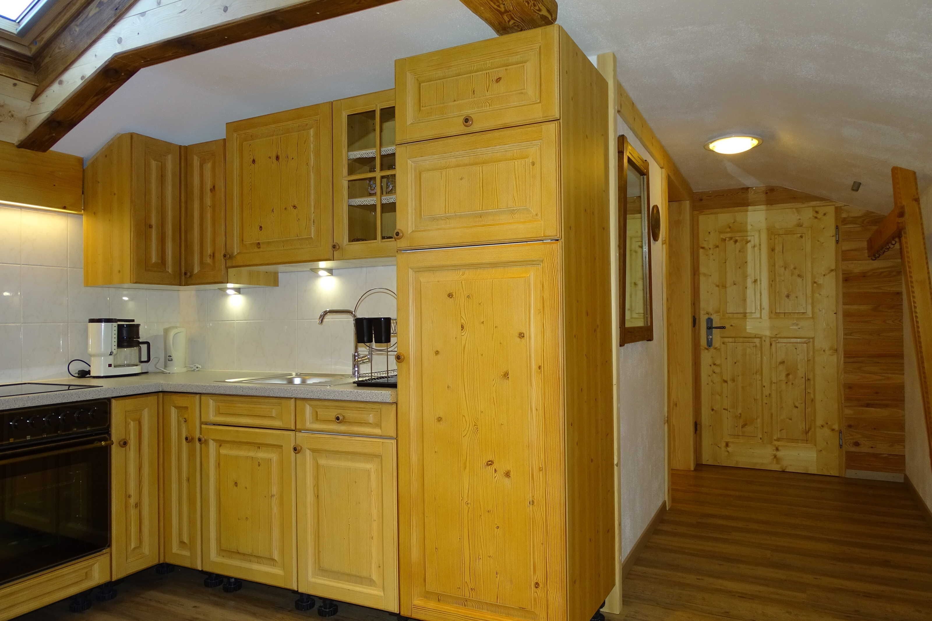 A kitchen with wooden cabinets, a coffee maker, and a sink.