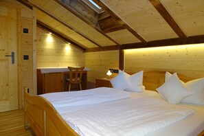 Un dormitorio de cabaña de madera con una cama, una silla, una mesita de noche y un escritorio.