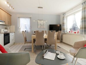 A modern kitchen with a dining area, a flat-screen TV, and a view of the Eiffel Tower.