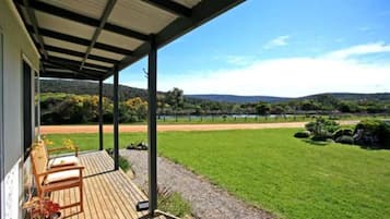 A covered outdoor area with a view of a grassy field and hills.