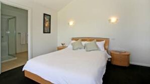 A bedroom with a bed, bedside tables, and a door.