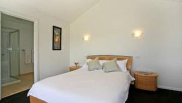 A bedroom with a bed, bedside tables, and a door.