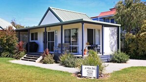 A small, single-story building with a covered porch, a signboard, and a well-maintained lawn.