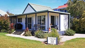 A small, single-story building with a covered porch, a signboard, and a well-maintained lawn.