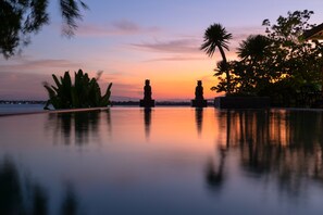 Una vista tranquila de la piscina al atardecer, con estatuas y plantas tropicales.