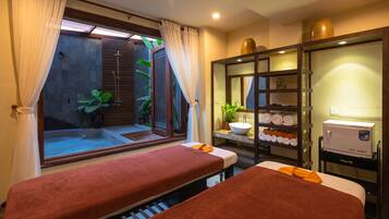 Relax in a serene space with a massage table, large window, and soothing views of a water feature and greenery.