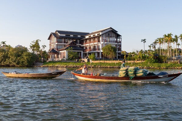 Dos barcos en un río tranquilo con un edificio grande al fondo.