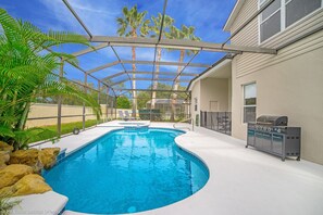 Une piscine entourée de parois en verre, un barbecue et une vue sur des palmiers.