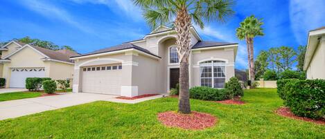 A single-story house with a garage, a well-maintained lawn, and a palm tree in the front yard.