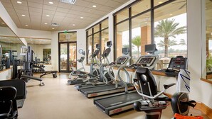 Une salle de sport équipée de tapis de course, de vélos d’exercice et d’appareils de musculation.