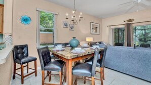 Un coin repas avec une table en bois, des chaises en cuir noir, un lustre et un grand vase.