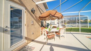 Une terrasse couverte avec une table et des chaises, une piscine et une vue sur les environs.