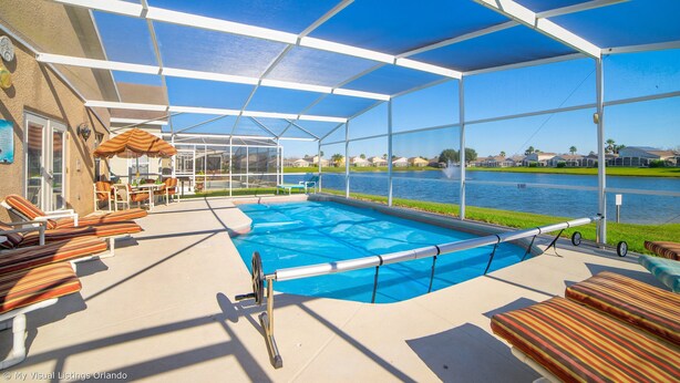 Une piscine extérieure avec des chaises longues et un espace abrité, donnant sur une étendue d’eau.