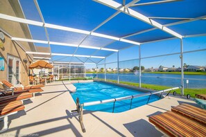 Ein Pool im Freien mit Liegestühlen und einer überdachten Liegefläche, mit Blick auf ein Gewässer.