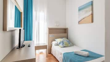 Quarto de hotel com cama, escrivaninha com televisão, janela com cortinas e um quadro na parede.