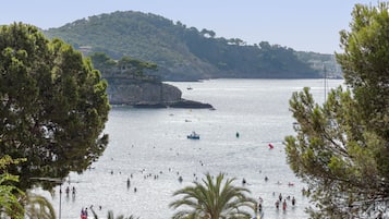 A coastal view with a beach, people swimming, and boats.