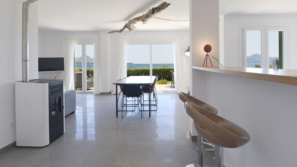 A modern kitchen with a dining area, a TV, and a view of the sea. - In the middle of Pollensa Bay (Apto Garrover A) (Port de Pollença)