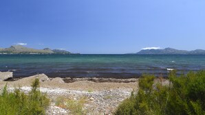 A coastal landscape with rocky shores, clear blue water, and distant mountains. - In the middle of Pollensa Bay (Apto Garrover A) (Port de Pollença)