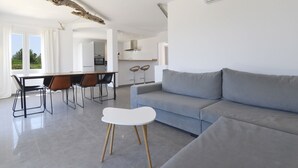 A modern living room with a grey sofa, a dining table with chairs, and a white coffee table. - In the middle of Pollensa Bay (Apto Garrover A) (Port de Pollença)