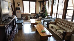 A cozy living room with a fireplace, a Christmas tree, and a large window. - Hotel Hakuba Powder Republic (Hakuba)