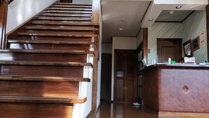 A wooden staircase leading to a reception area with a wooden desk and a framed picture on the wall. - Hotel Hakuba Powder Republic (Hakuba)