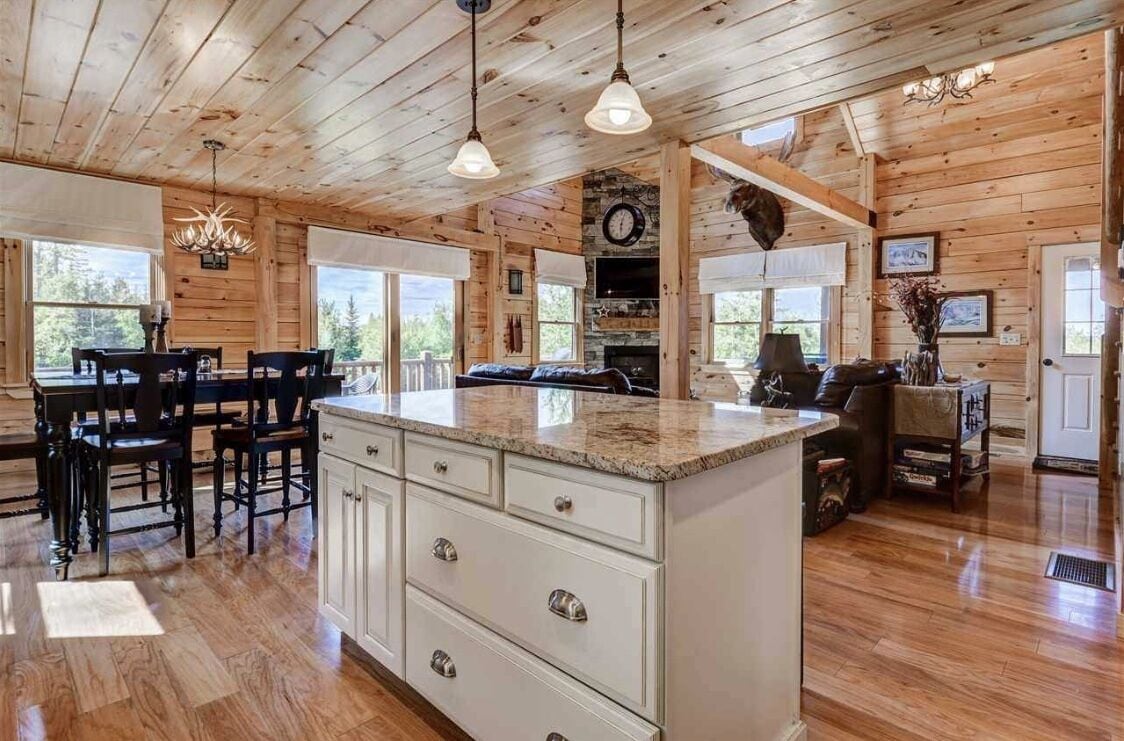 A wooden cabin interior with a kitchen, dining area, and living room.