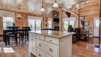 A wooden cabin interior with a kitchen, dining area, and living room.