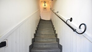 A staircase with a handrail, white walls, and a light fixture at the top.