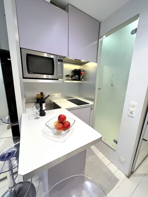 Uma cozinha moderna com micro-ondas, máquina de café e uma tigela de frutas no balcão.