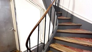 Una escala de fusta amb barana negra i una porta al final.