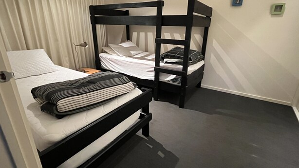 Un lit superposé avec un oreiller et une couverture à rayures sur le lit du bas.