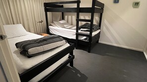 Un lit superposé avec un oreiller et une couverture à rayures sur le lit du bas.