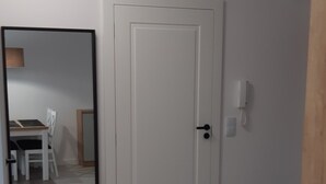 Une pièce avec une porte blanche, un miroir et un plancher en bois.