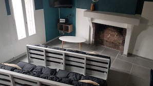Une pièce avec un lit blanc, une petite table blanche, une cheminée en briques et un mur de couleur turquoise.