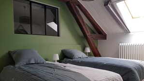 Une chambre avec deux lits, une fenêtre, une lampe et un radiateur.
